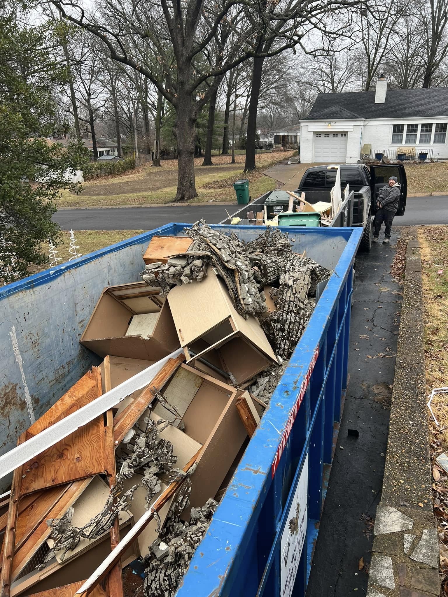 A loaded roll-off dumpster in a residential driveway
